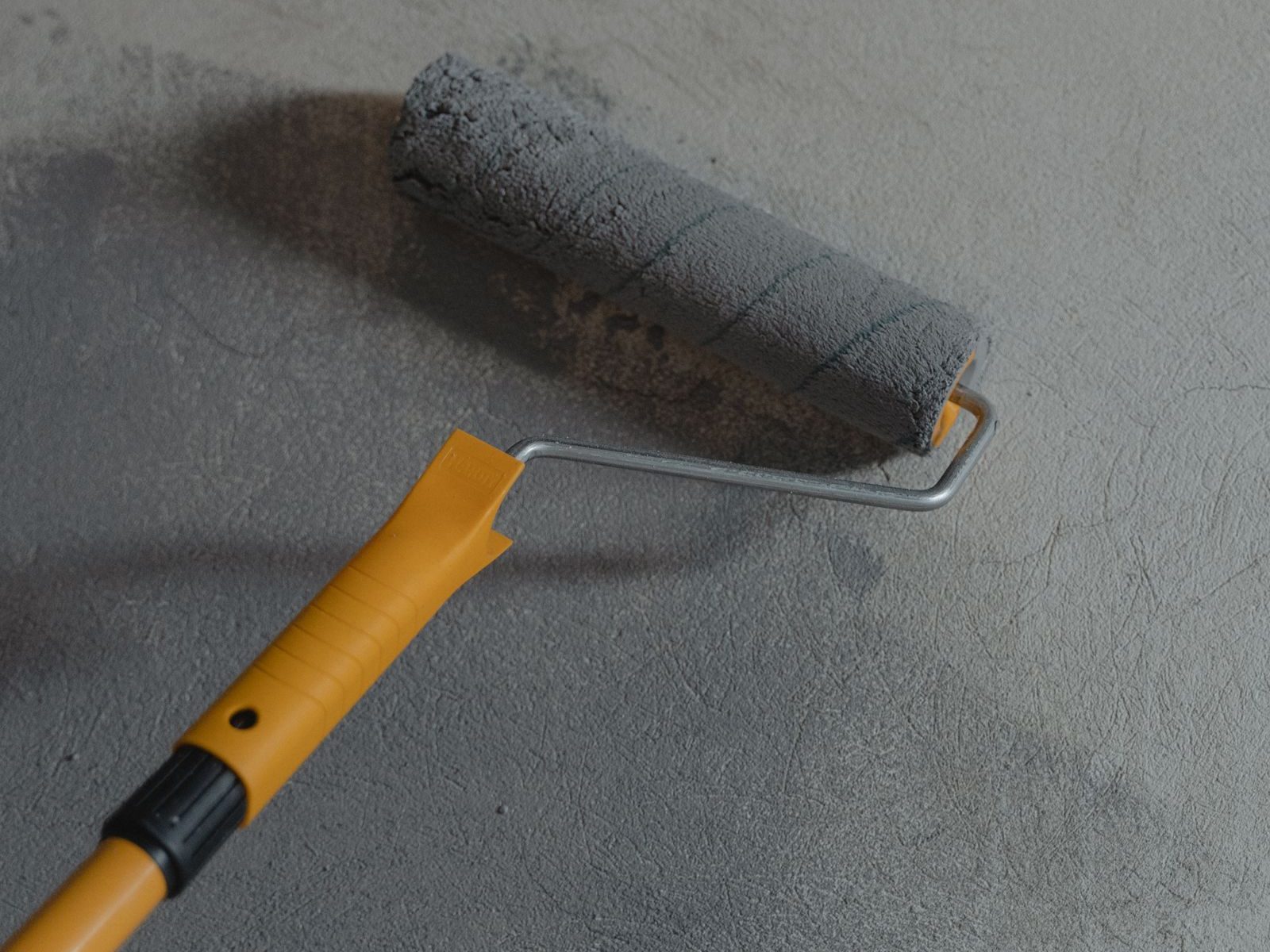 Roller applying gray floor coating